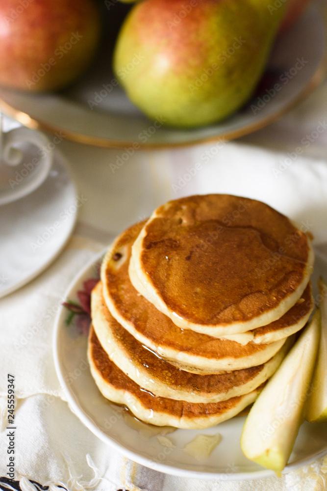 Fresh baked pancakes with honey, pear and tea closeup Fresh baked pancakes with honey, pear and tea closeup