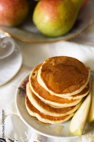 Fresh baked pancakes with honey, pear and tea closeup