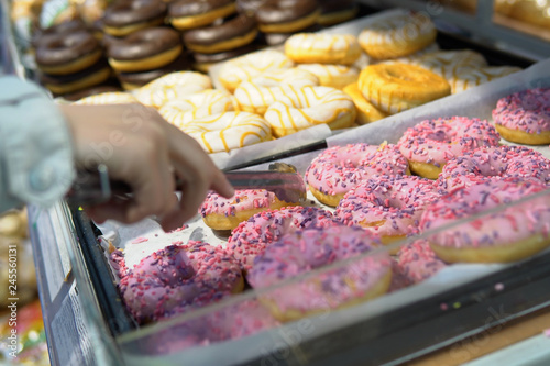 Someone takes a donut from a shelf in the confectionery department.