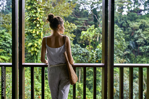 Brunette girl with wicker bag on wooden terrace on green nature background © Andriy Bezuglov