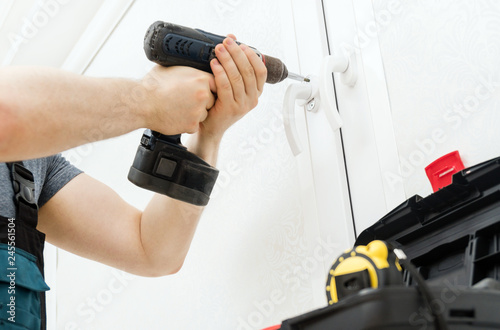 Professional handyman fixing window handle at home.