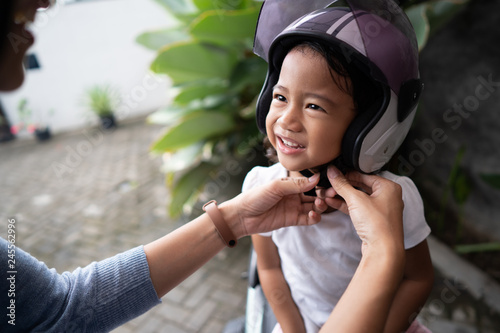 mom helped her daughter to put on helmet