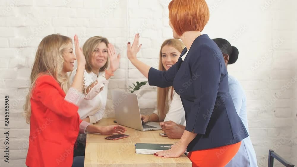 Multinational group of cheerful female students taking an active part in a discussion while sitting in a university hall. Multinational group of cheerful female students taking an active part in a discussion while sitting in a university hall.