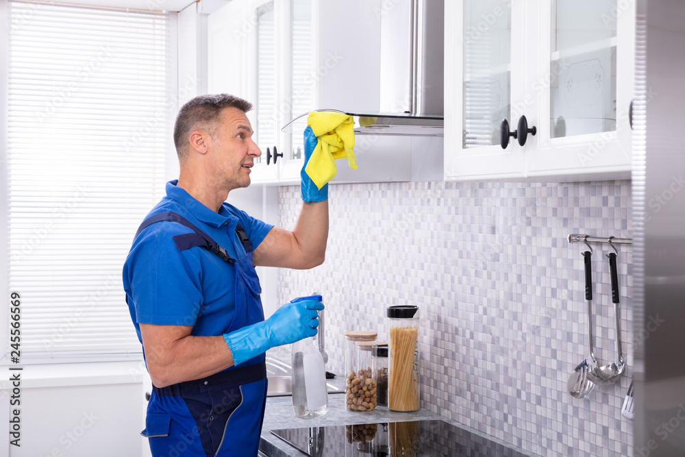 Male Janitor Cleaning Cooker Hood With Napkin And Detergent Male Janitor Cleaning Cooker Hood With Napkin And Detergent