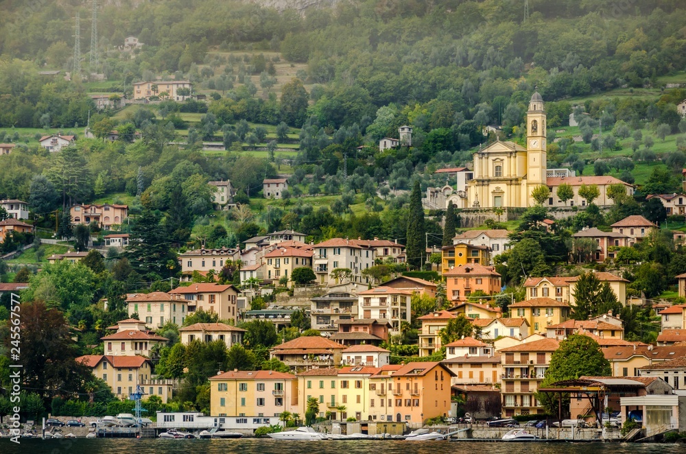 View of village in forest in Lake Como from ferry at sunset, chu