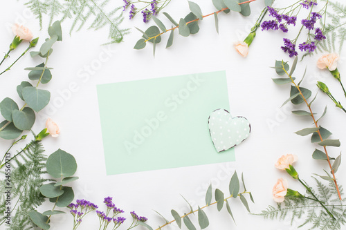 Flowers composition. Paper blank, carnation flowers, eucalyptus branches on pastel background. Flat lay, top view, copy spaceFlat lay stiil life.