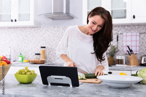 Woman Using Digital Tablet While Cooking Food