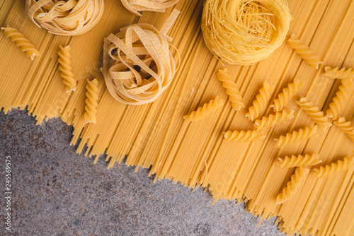 Raw spaghetti pasta and tagliatelle arranged flat with top view. A simple take on the various types of pasta that we can use when cooking. A frame with a free place an description. Copy space. 