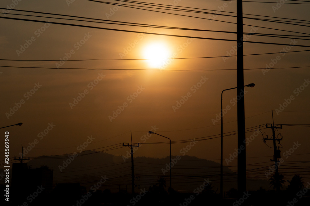 Electric pole with orange light with Silhouette of mountains and cities.