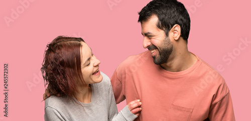 Couple in valentine day smiling a lot over isolated pink background