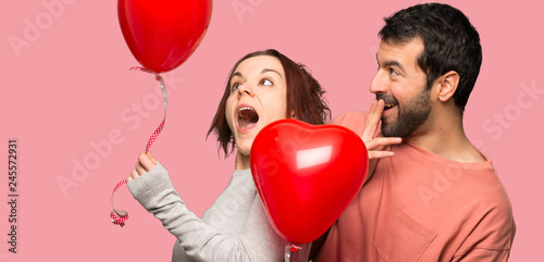 Couple in valentine day with balloons with heart shape over isolated pink background