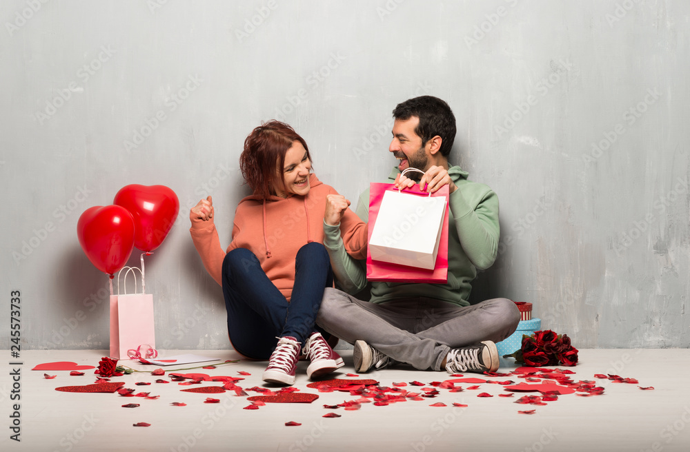 Couple in valentine day holding shopping bags in victory position Couple in valentine day holding shopping bags in victory position