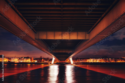Symmetric underside of the bridge at night view with warm color tones and long exposure water. Köln, Cologne in Germany © Ricardo