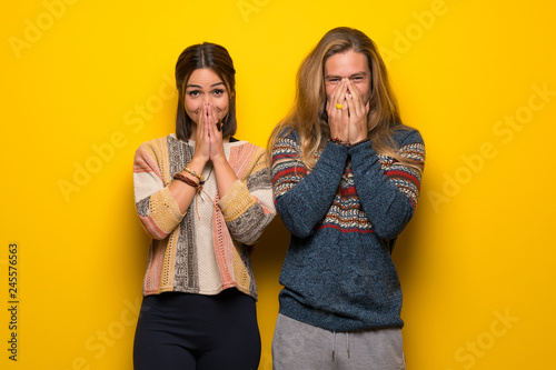 Hippie couple over yellow background smiling a lot