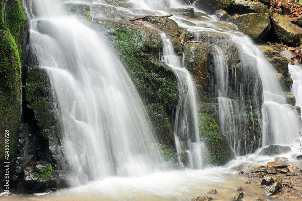 bottom of the beautiful waterfall among the forest. wonderful nature scenery in spring or summer. huge mossy boulders. refreshing stream