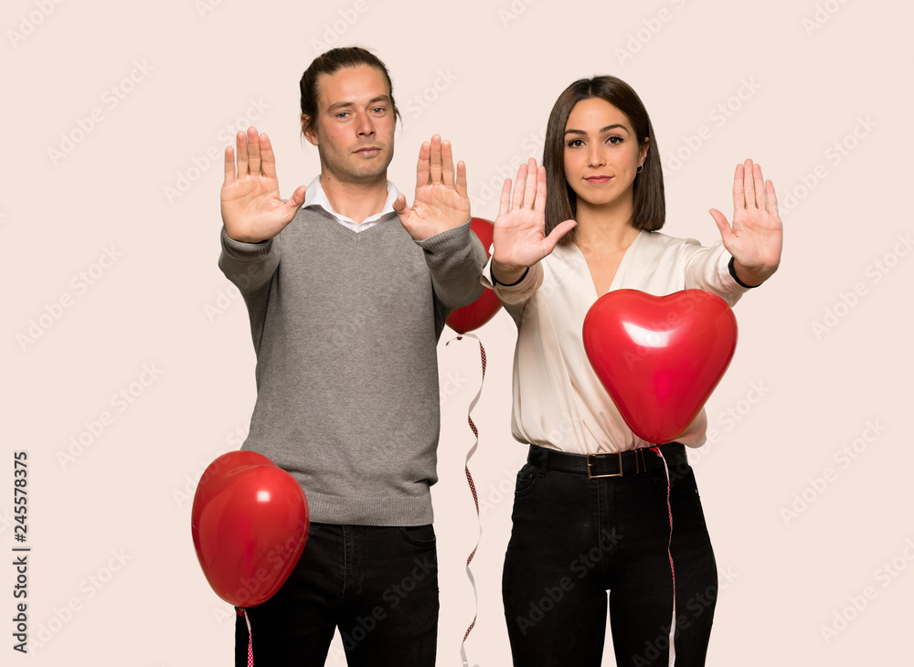Couple in valentine day making stop gesture for disappointed with an opinion over isolated background Couple in valentine day making stop gesture for disappointed with an opinion over isolated background