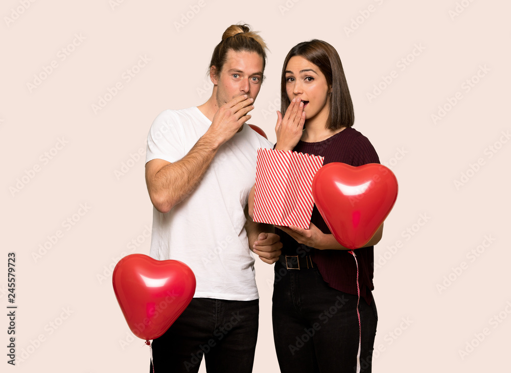 Couple in valentine day eating popcorns over isolated background Couple in valentine day eating popcorns over isolated background