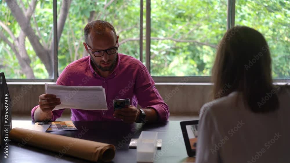Businesspeople with documents and cellphone working by table at home office