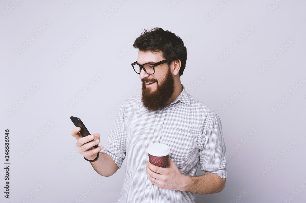 Handsome smiling bearded man take a coffee break and chek his mail Handsome smiling bearded man take a coffee break and chek his mail