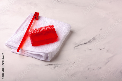 Red toothbrush and natural soap on a marble background