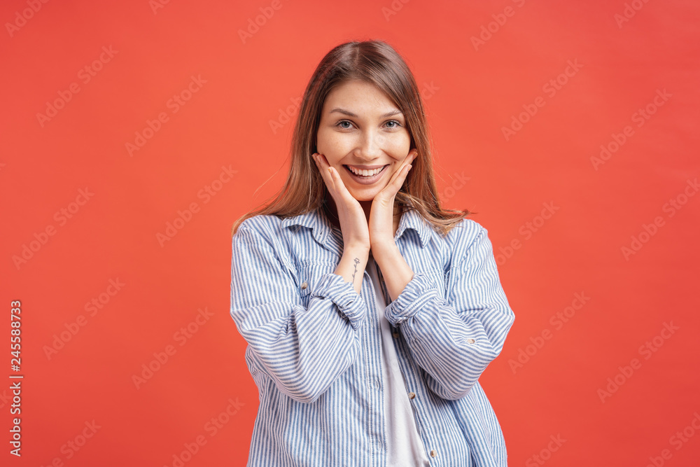 People emotions - portrait of surprised positive girl over red background People emotions - portrait of surprised positive girl over red background