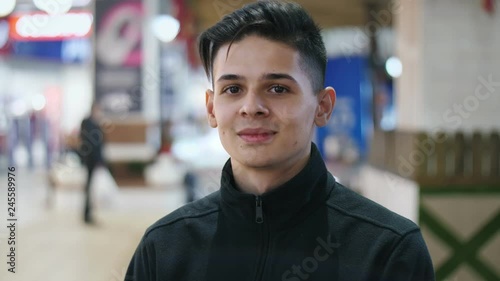 Young teen sitting in a large mall with raised collar feeling chilly in slo-mo  