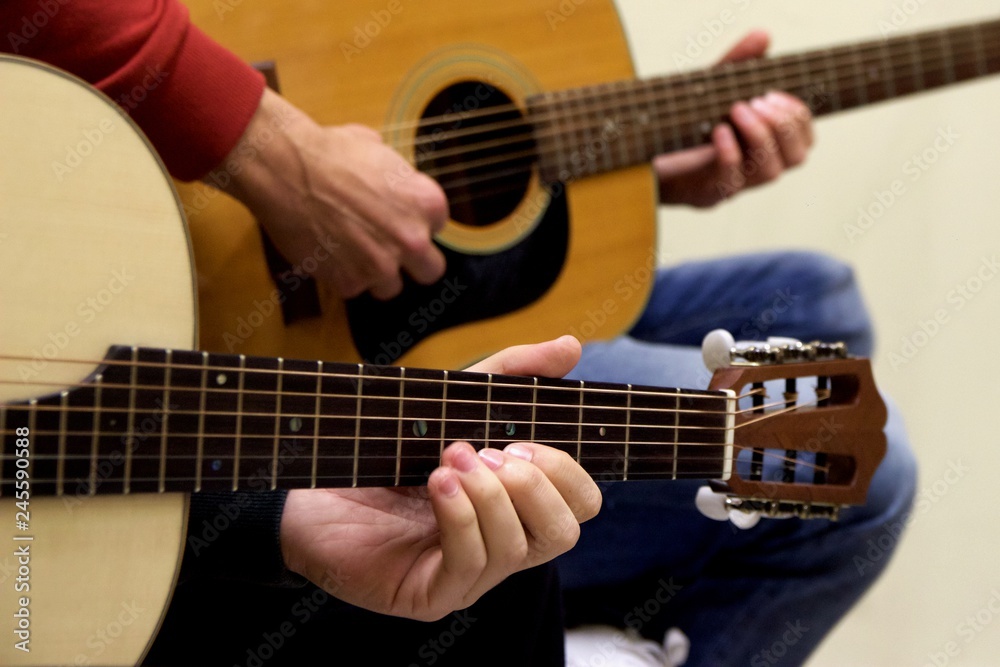 Closeup at left hand of guitarist learning how to play acoustic guitar instrument of traditional Greek music of 