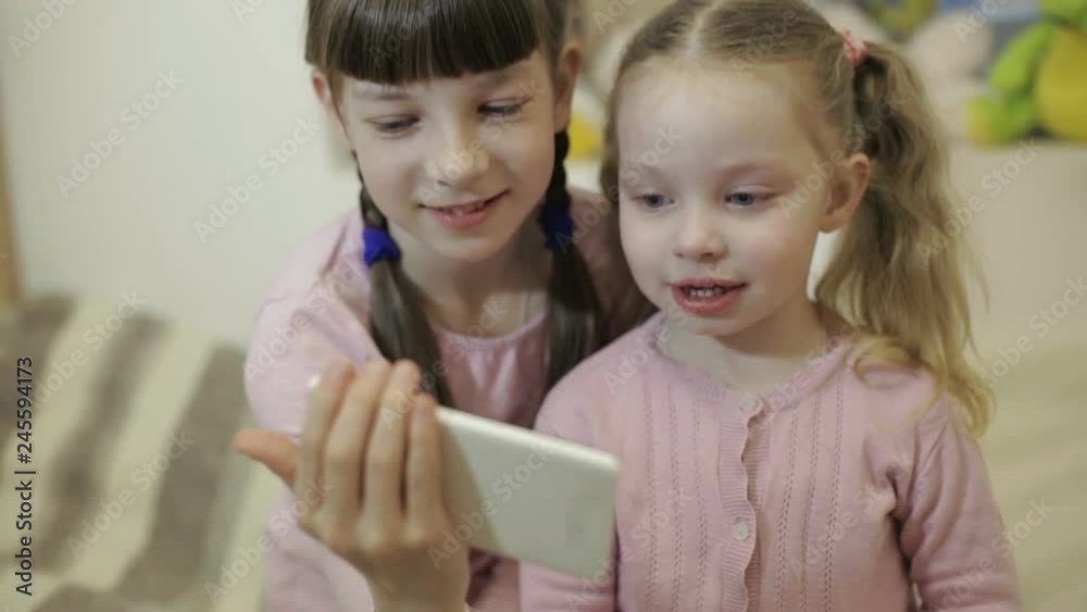 two little girls having video chat using smartphone with their friends two little girls having video chat using smartphone with their friends
