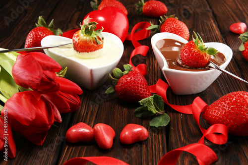 Valentine Chocolate fondue melted with fresh strawberries and dark and white chocolate. Tublips and sugar hearts. photo