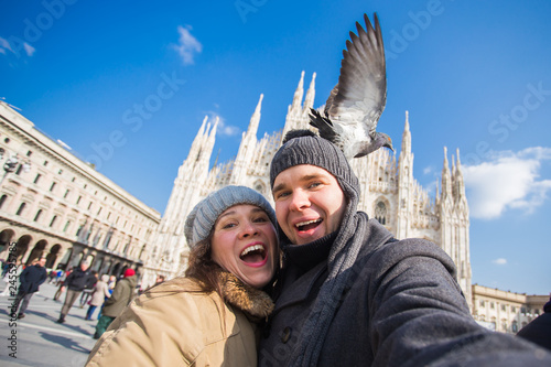 Couple taking self portrait with pigeon in Duomo square in Milan. Winter traveling, Italy and relationship concept