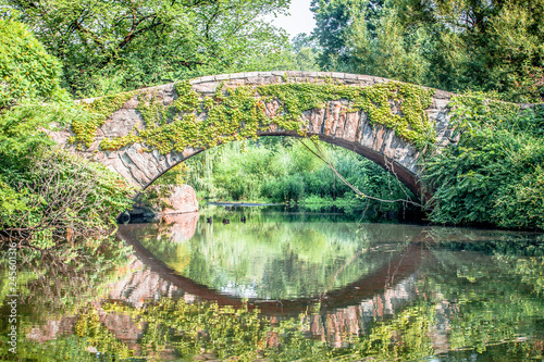 Beautiful Gapstow bridge reflecting in water in Central Park, New York City during summer sunny day
