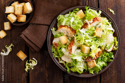 Caesar salad with grilled chicken meat, fresh lettuce, parmesan cheese and fried croutons. Classic North American cuisine. Top view