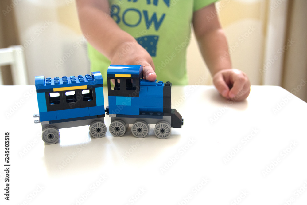 boy play with constructor train made with colored bricks close up portrait