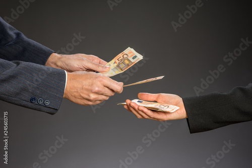 Deal! Businessman paying money  (fifty euros) to businesswoman. Woman and man hand on a gray background.