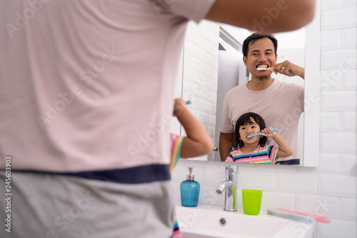 father and daughter brushing teeth together