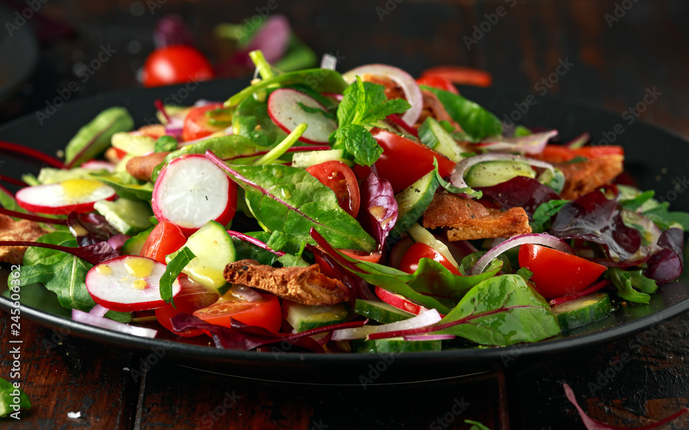 Traditional fattoush salad on a plate with pita croutons, cucumber, tomato, red onion, vegetables mix and herbs