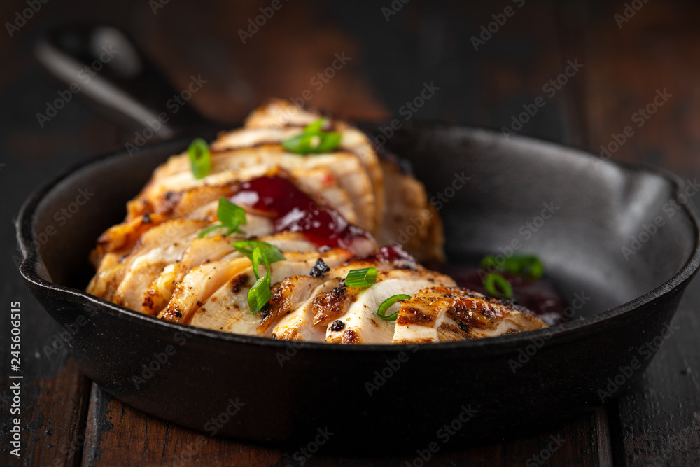 Grilled sliced chicken breast with cranberry sauce in mini cast iron frying pan Grilled sliced chicken breast with cranberry sauce in mini cast iron frying pan