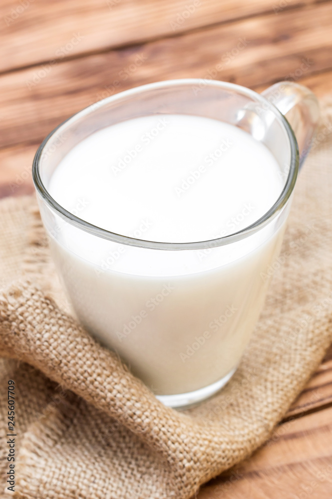 Glass cup of milk with sack napkin on the wooden table. Top view. Glass cup of milk with sack napkin on the wooden table. Top view.