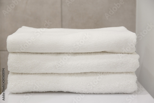 Stack of white clean towels on table in bathroom