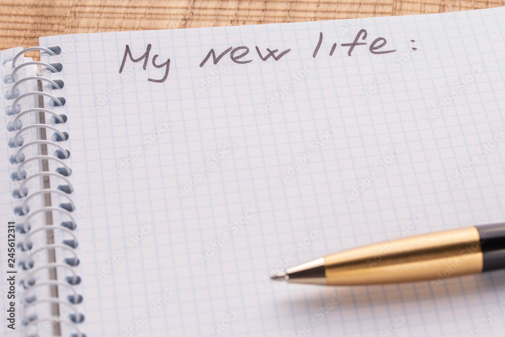 Top view workplace notebook and pen on wood table background. Inscription - my new life Top view workplace notebook and pen on wood table background. Inscription - my new life