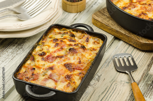Potato gratin with parmesan cheese, cream and cured bacon from South Tyrol. Tartiflette: baked potatoes with bacon and cheese close up. Scalloped potato casserole 