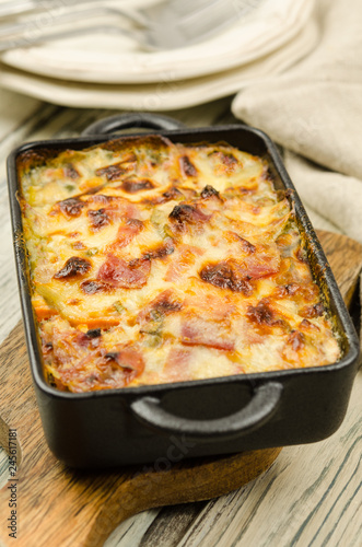 Potato gratin with parmesan cheese, cream and cured bacon from South Tyrol. Tartiflette: baked potatoes with bacon and cheese close up. Scalloped potato casserole 