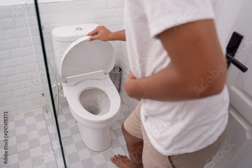 man hold his stomach painful in the toilet