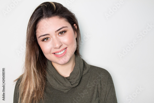 Portrait of young beautiful cute cheerful girl smiling looking at camera over white background. © Hazal