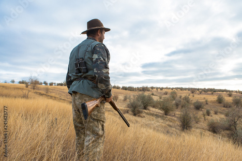 Hunter with a hat and a gun in search of prey in the steppe 