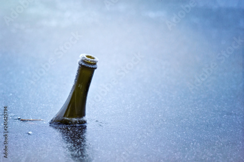 bottle of sparkling champagne wine frozen in ice in lake on new years day