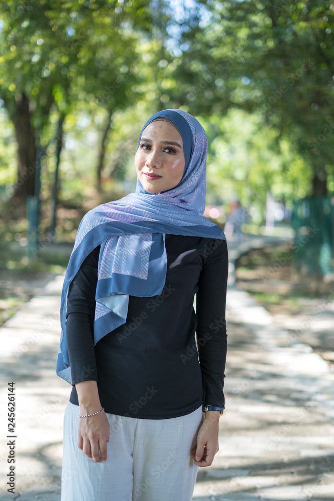 Happy Muslim Asian young woman in hijab posing at green park Happy Muslim Asian young woman in hijab posing at green park
