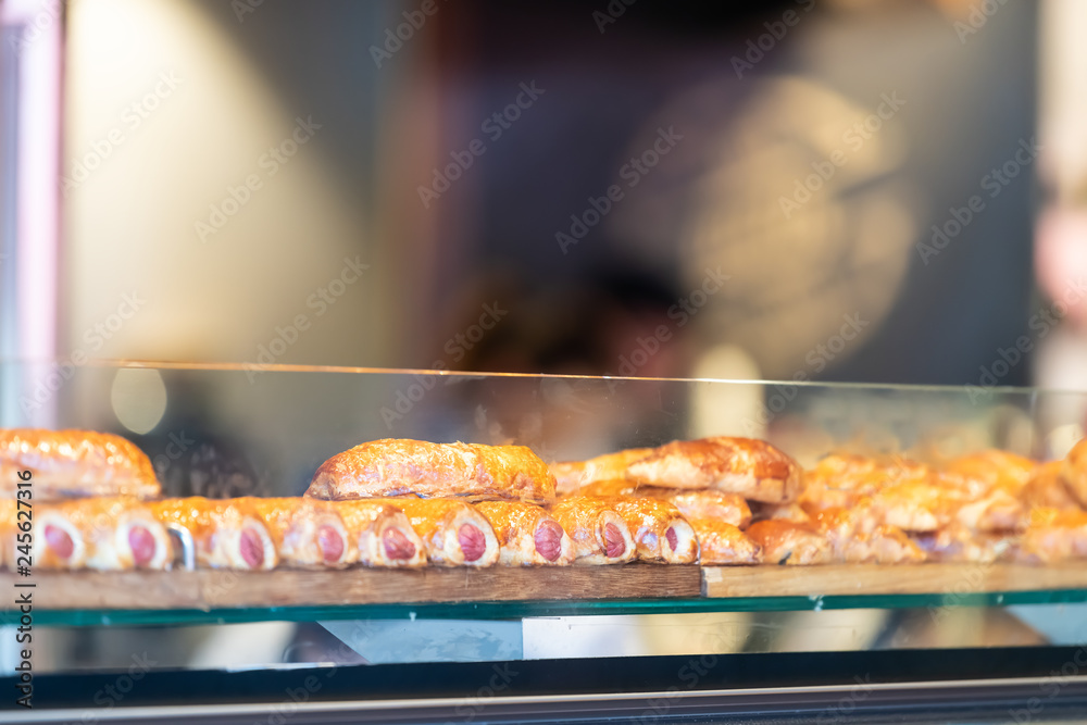 Glass display closeup of many baked goods bread desserts croissants on trays in breakfast gourmet bakery cafe with sausages Glass display closeup of many baked goods bread desserts croissants on trays in breakfast gourmet bakery cafe with sausages