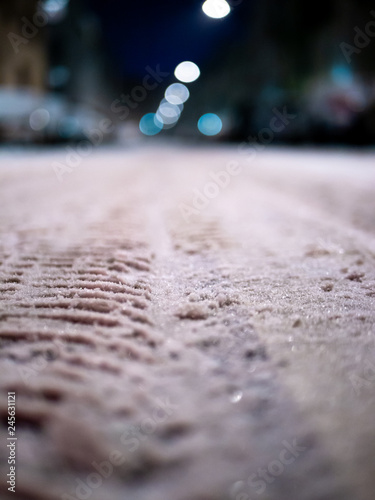 Close up shot of snowy street with tire marks