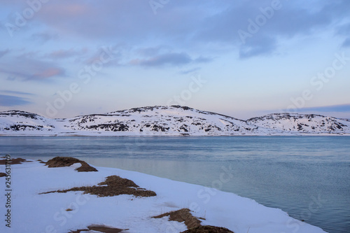 Arctic Ocean, winter time, snow shore, Russia, landscape of beautiful wild nature of north seas. Beautiful snow winter ice and cold landscape, picturesque view with mountains on horizon, sky clouds